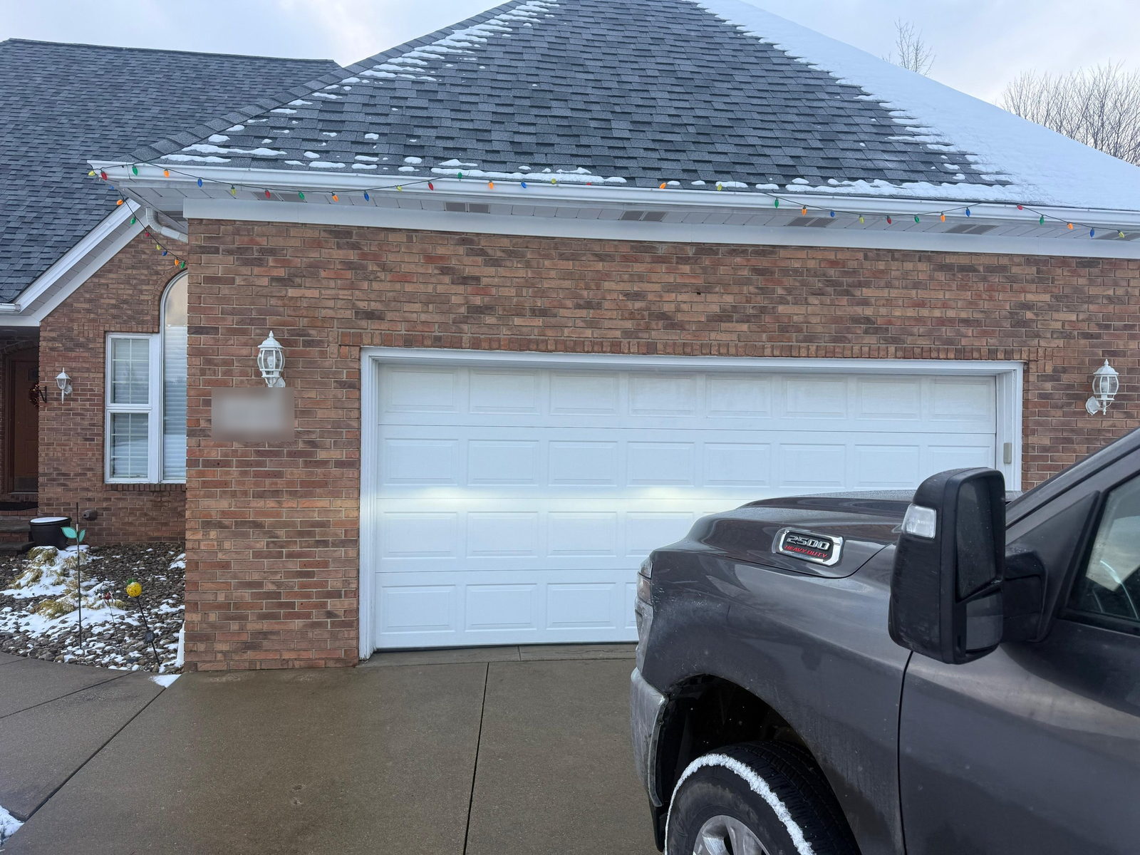 White long-panel double garage door on a brick home, closed, with a pickup truck in the driveway.