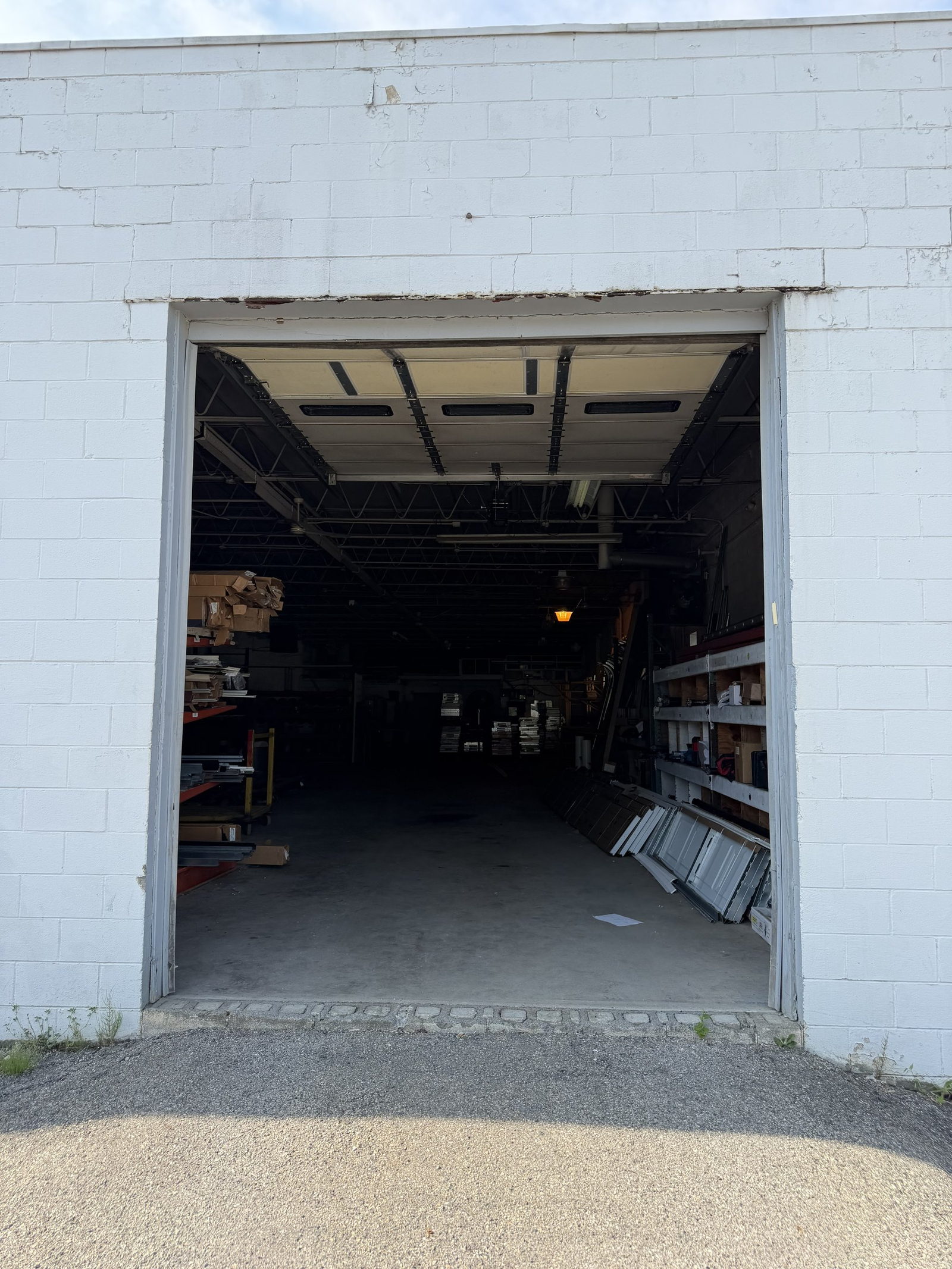 Open overhead door on a service building, with garage door panels and track stored inside.