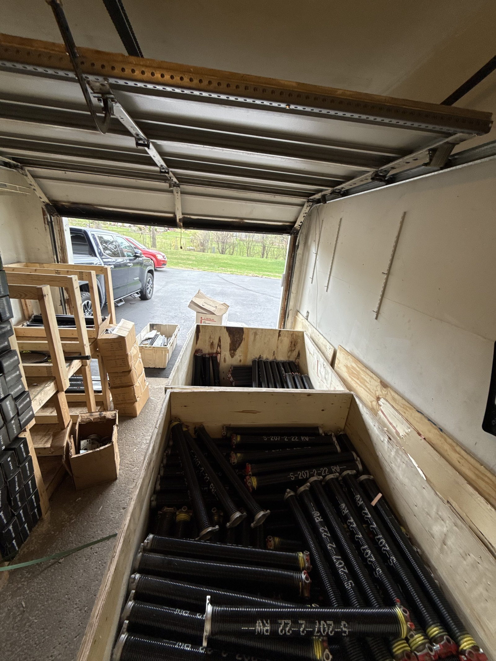 Crates of garage door torsion springs and boxes of hardware loaded in a work vehicle.