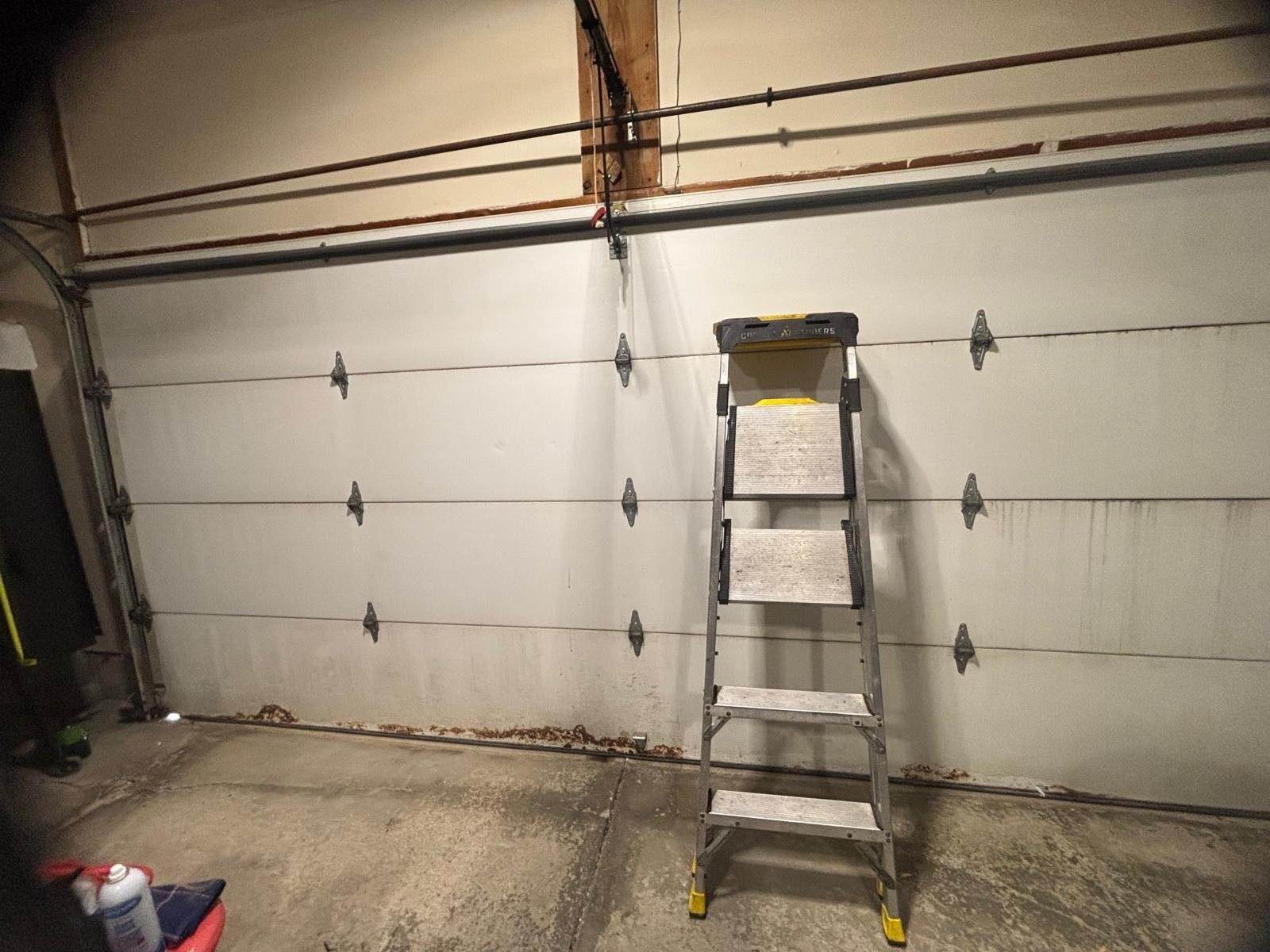 Inside face of a closed sectional garage door showing hinges and roller stems along each panel joint.