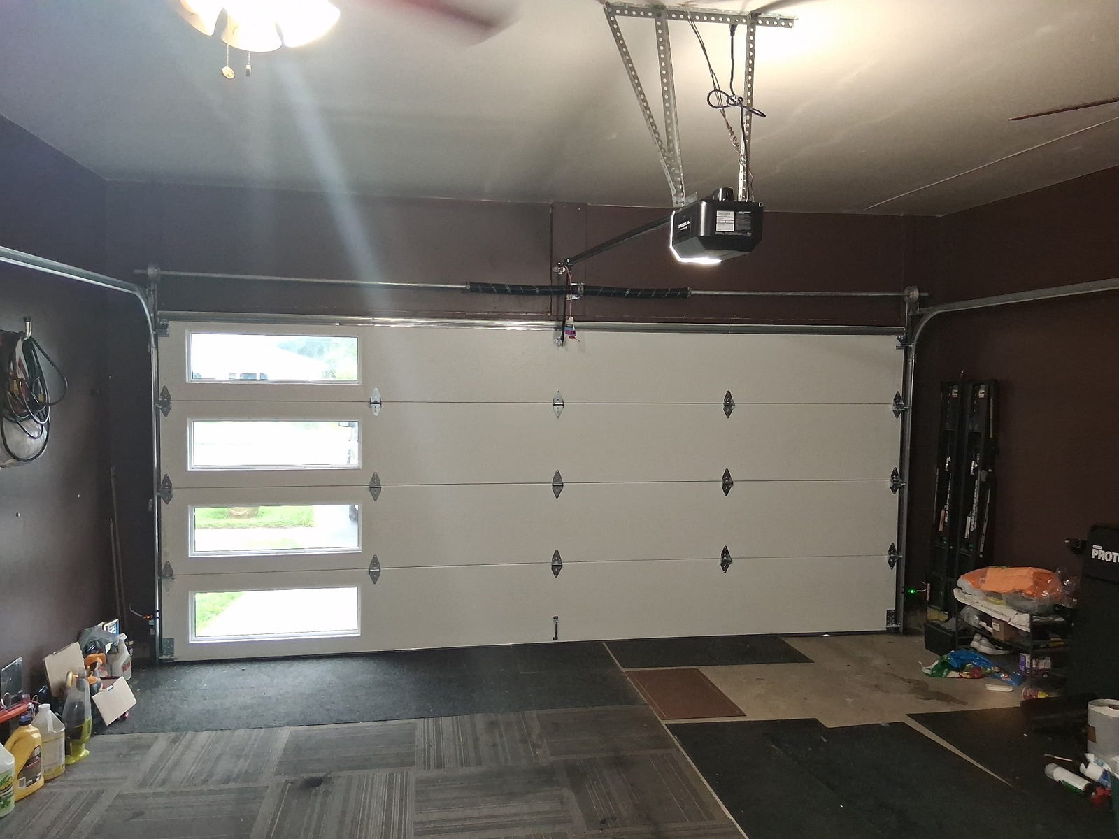 Garage interior with a windowed white sectional door and a chain-drive opener on a ceiling rail.