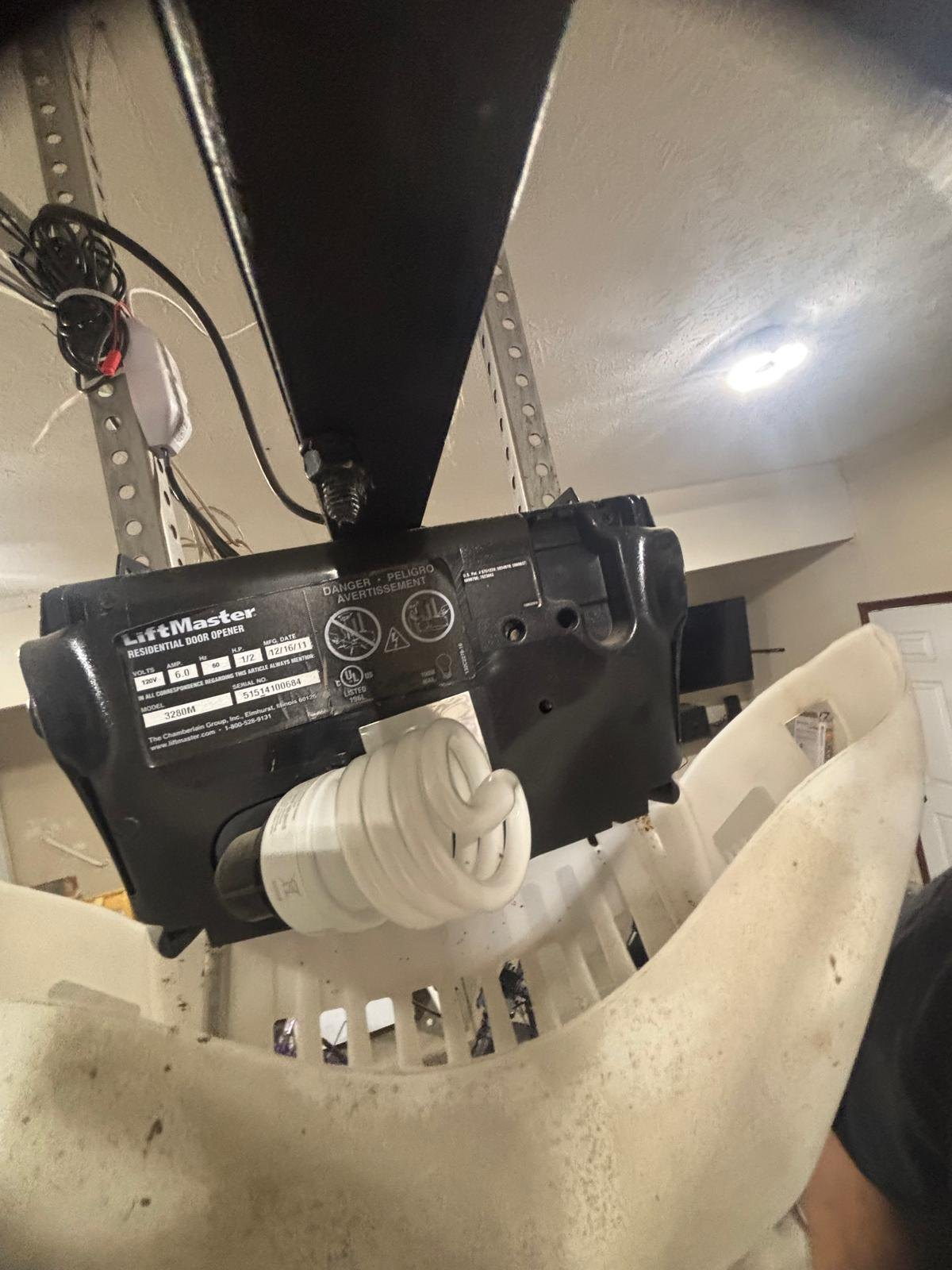 Close-up of a LiftMaster garage door opener motor head with the light lens open.