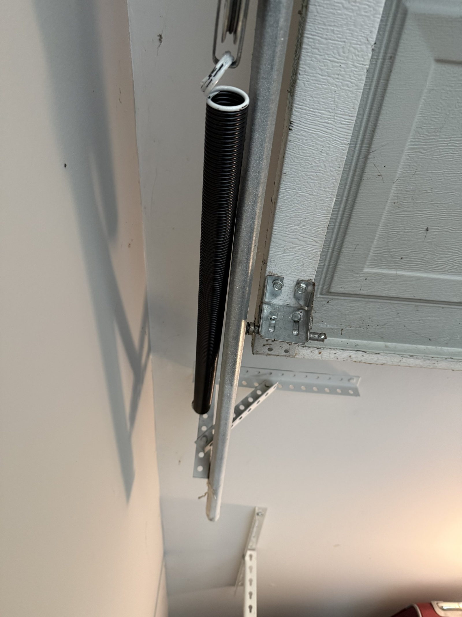 Extension spring mounted alongside the horizontal track above a garage door.