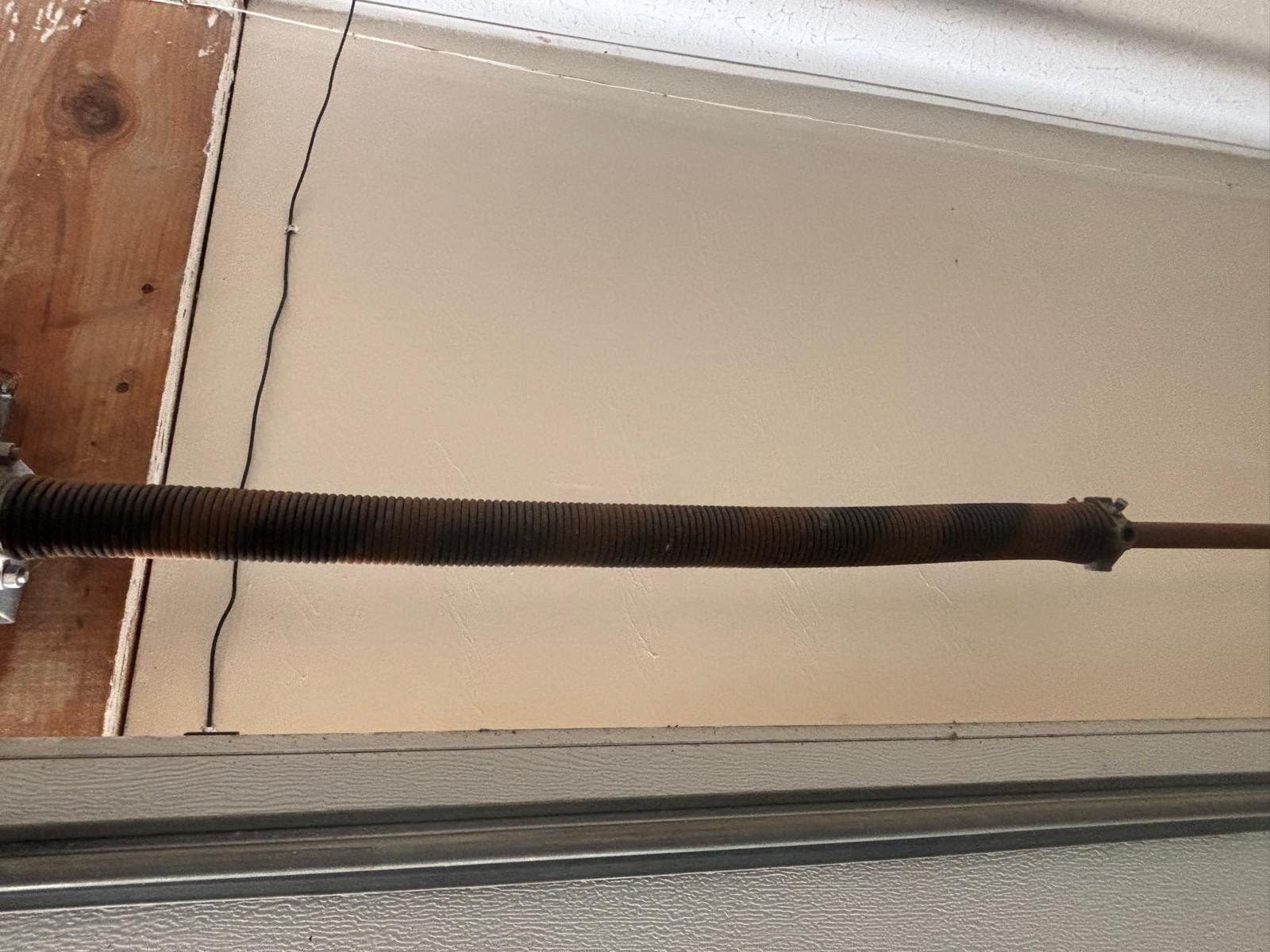 Torsion spring on the shaft above a closed garage door, mounted along the header.
