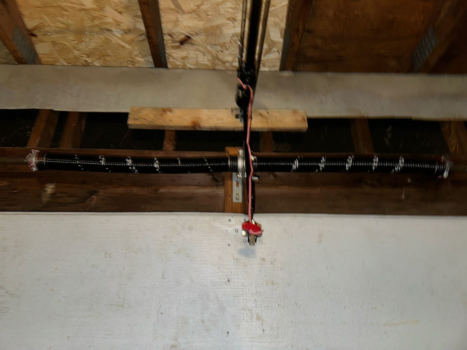 Torsion spring and center bearing plate mounted on the shaft above a garage door opening.